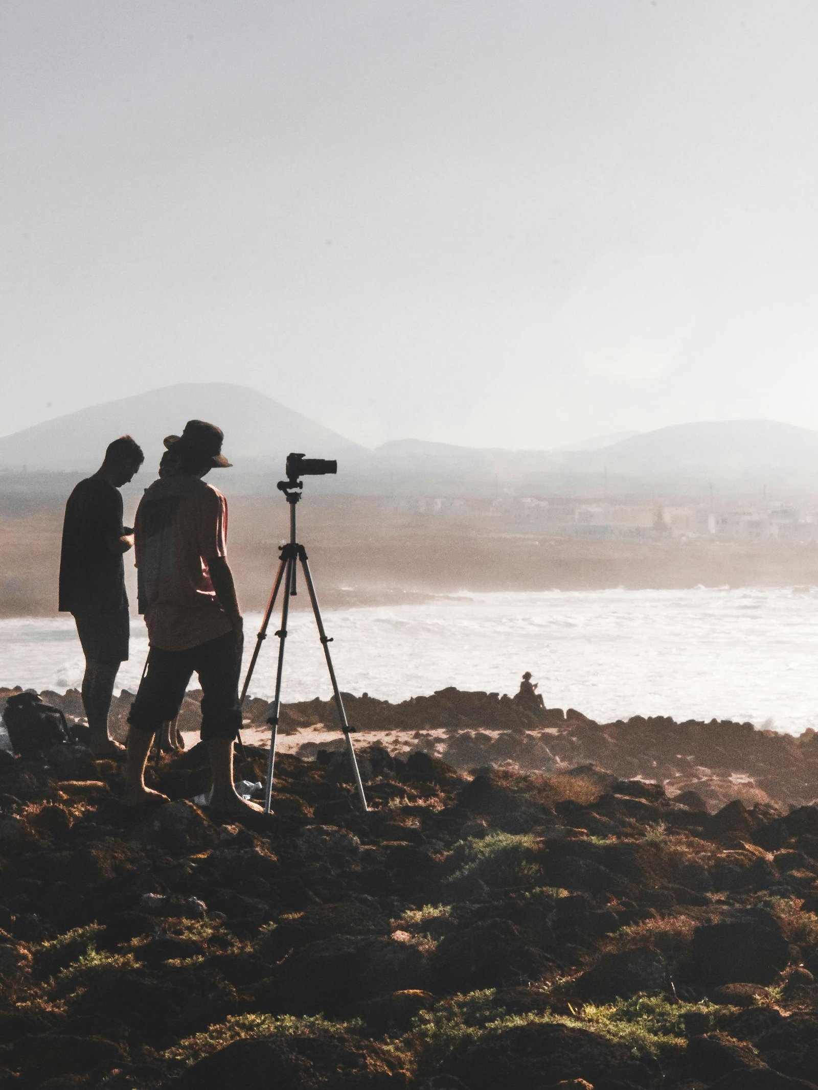 Two Men Standing on Rock Taking Photo Body of Water